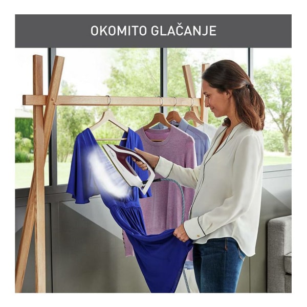 Žena žehlí modré šaty pomocou parného generátora Tefal Pro Express Ultimate II GV9721E0; viditeľná para a stojan na šaty.